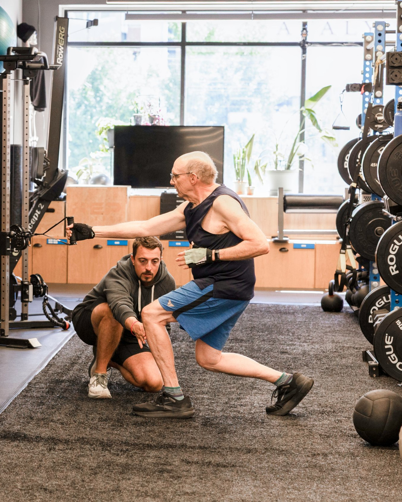 A trainer guiding an older client through a cable lunge